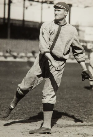 Walter Johnson striding through his pitching delivery in a black-and-white photograph